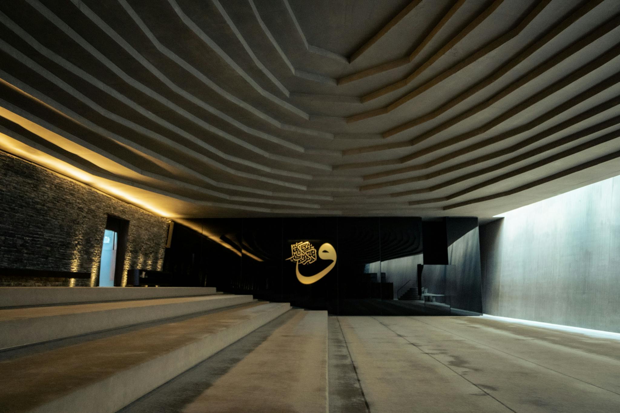 Stunning modern mosque interior featuring elegant Arabic calligraphy and dramatic lighting.